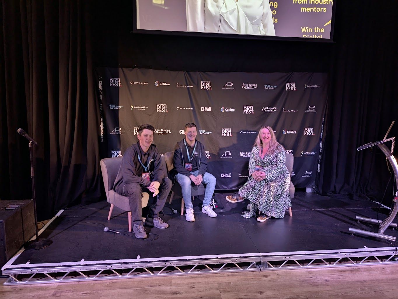 Tyler Mortimer-Wise and Ben McCormick presenting on stage at DigiFest, hosted by Ellie Hale.